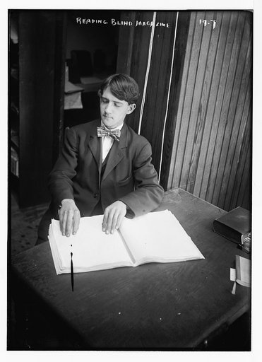 Blind man reading magazine