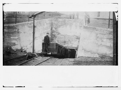 Miner decending in rail car at mouth of mine