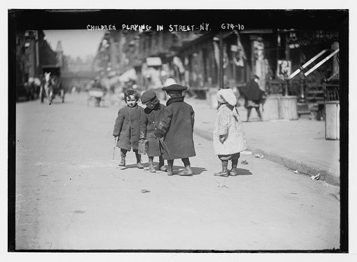 Children bundled in warm clothes playing in street, New York
