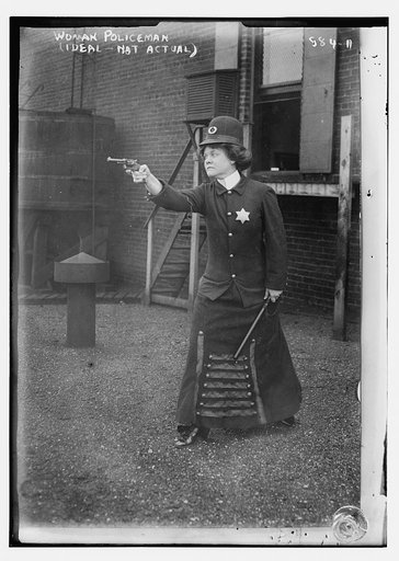 Policewoman posing with pointed gun and bobby stick