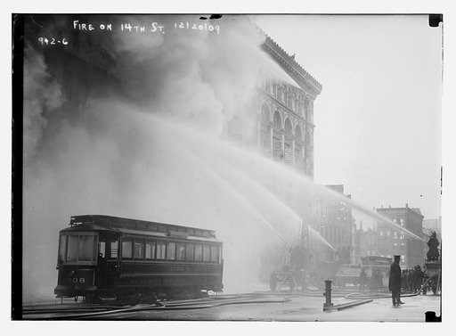 Firemen spraying burning building on 14th St., trolley in foreground, New York