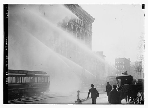 Firemen spraying burning building on 14th St., trolley in foreground, New York