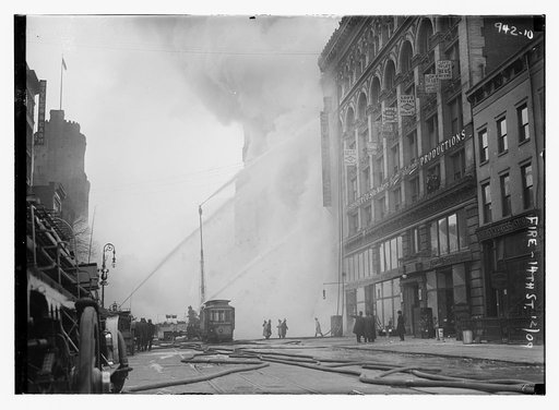 Firemen spraying burning building on 14th St., trolley in foreground, New York