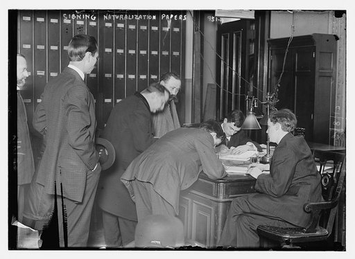 New citizens signing naturalization papers in judge's chambers