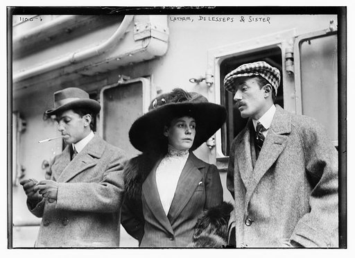 Latham, DeLesseps and sisters, standing beside railroad train