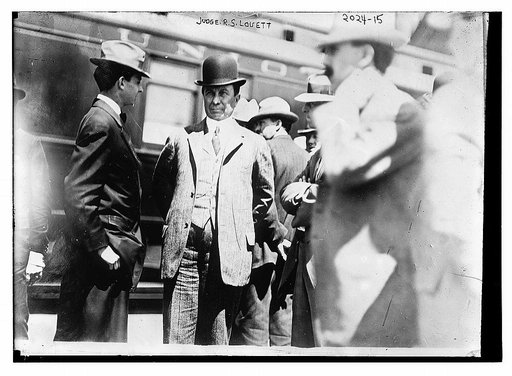 Judge R.S. Louett; Three-quarter view of Louett standing with a group of men in front of train