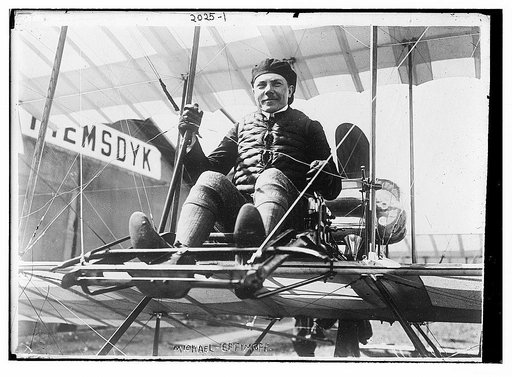 Michael Effimoff seated in flying costume in a primitive plane