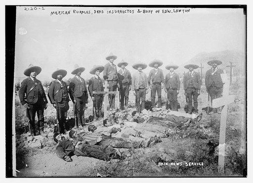 Mexican rurales, dead insurrectos, and body of Edw. Lawton lying in pit, with surrounding guard