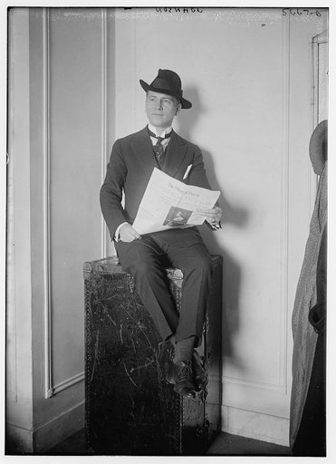 Johnson [seated on a trunk, reading newspaper
