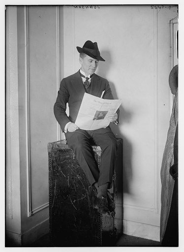 Johnson [seated on a trunk, reading newspaper