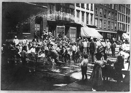 N.Y.C. children in hot weather, playing under spray of fire hydrant, policemen standing by