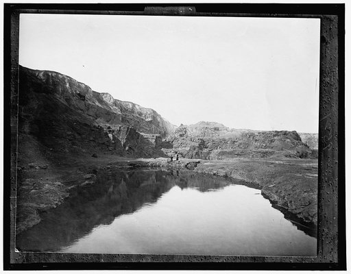 Two women by water, rocky cliffs in background