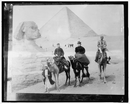 Couple on camels in front of the Sphinx and pyramid of Jizah, Egypt