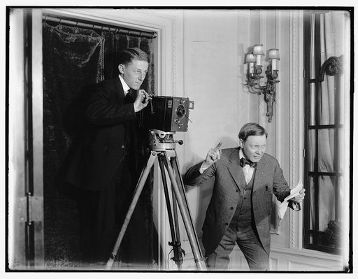 Two men using a movie camera indoors