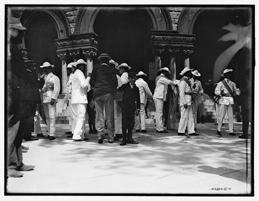Soldiers and newsboy in plaza, probably Havana, Cuba, or possibly Mexico