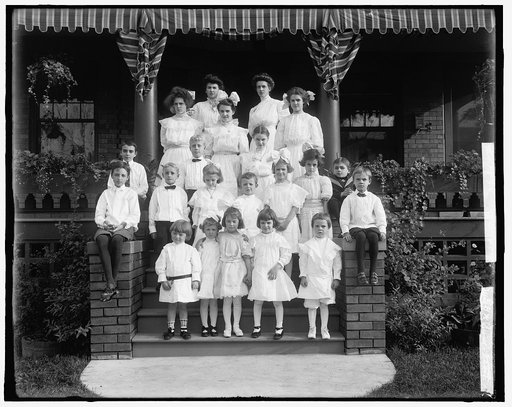 Children and women on steps of house, possibly school children and teachers
