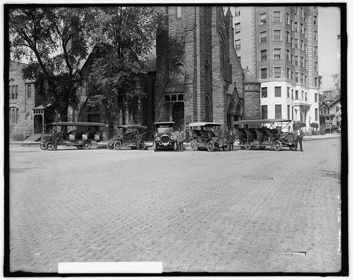Tourist buses in front of church with Hotel Tuller at right, Detroit