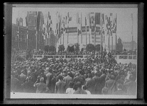 Crowd at ceremony next to tower with flags