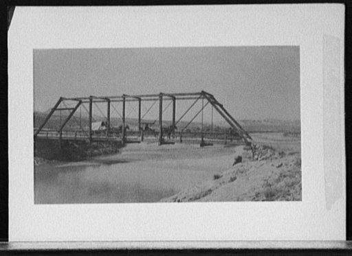 Carriage and wagon crossing bridge over river bluff
