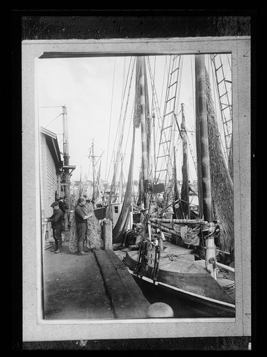 Fisherman with net by his boat at wharf