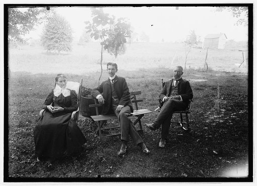 Unidentified men and woman seated in yard