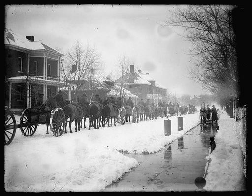 Wagon procession, snow covered street and houses