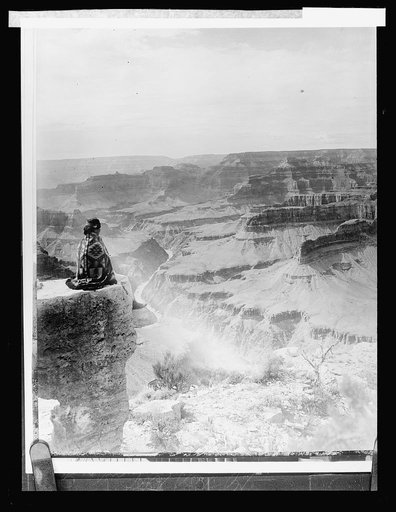 Native American seated on the edge of the Grand Canyon, Arizona