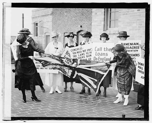 A group of women on the sidewalk, carrying signs against America's involvement on the side of the English against the Irish, and tearing up a British flag, June 3, 1920