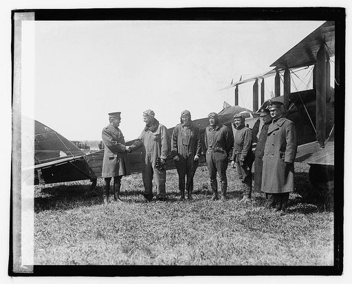 Group of men standing next to biplane], 3/29/21