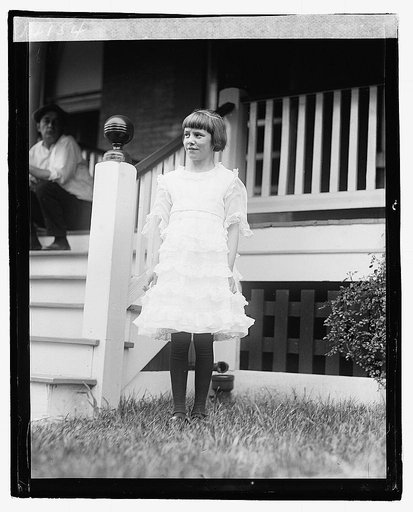 Unidentified girl standing in front of porch