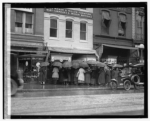 Rear view of group of women with umbrellas standing outside of store