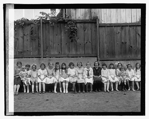 Children seated in front of fence], 8/31/22