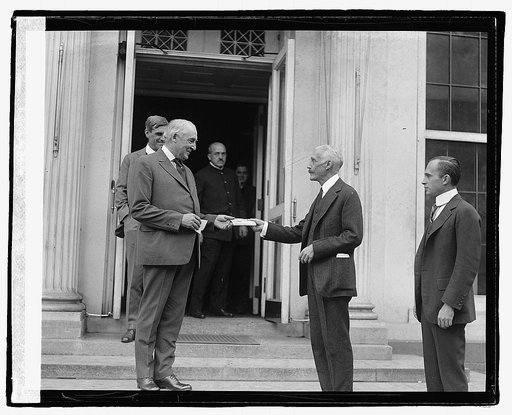 Treasury Secretary Andrew Mellon hands three new Treasury savings certificates to President Warren G. Harding, Harding's secretary tGeorge B. Christian Jr, to the left of Harding and Lew Wallace, Jr. to the right of Harding]10/27/22