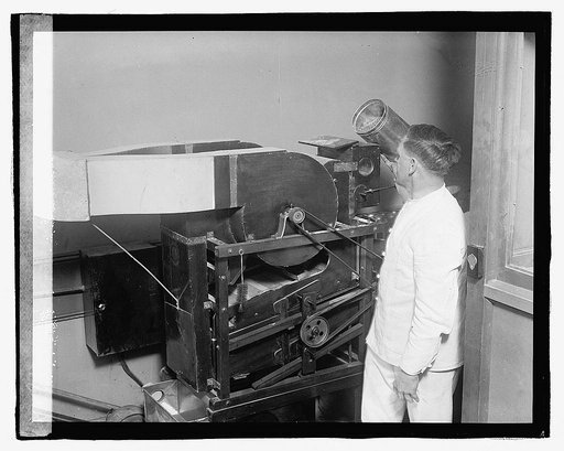 Man with unidentified machine, possibly a blower or enlargement print dryer
