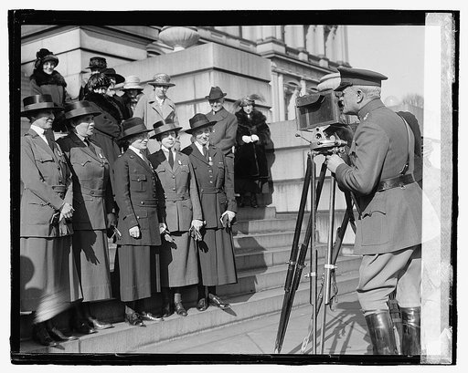 Uniformed man photographing group of unidentified uniformed women and man, ceremony on steps