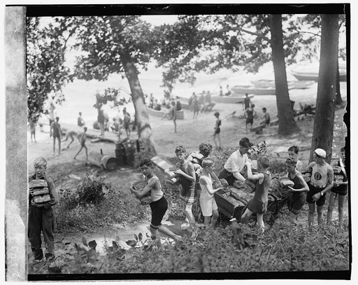 Group of boys carrying loaves of bread from wagons near beach