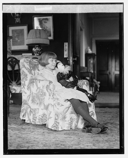 Girl seated in chair with doll