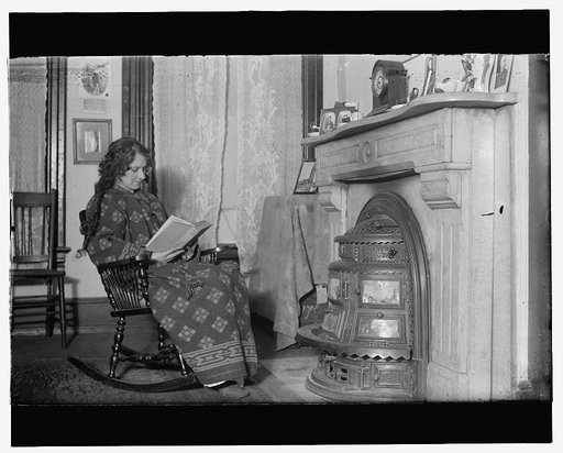Woman seated in front of coal stove, c.1914