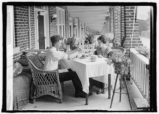 Man and woman eating at table on front porch of row house
