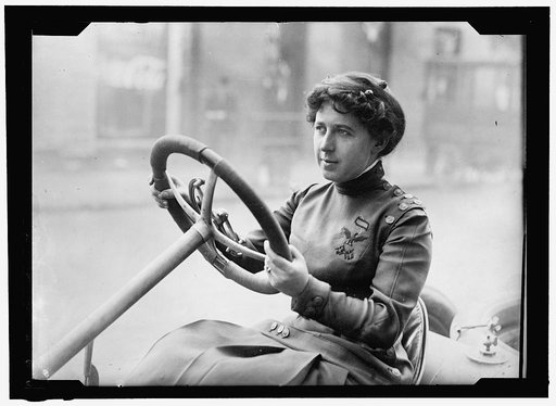 Race car driver Joan Newton Cuneo, seated in racing car, facing left