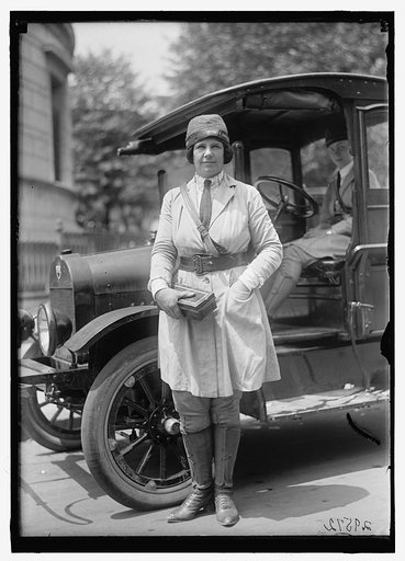 Woman in uniform wearing hat with label: "War Camp Community Service"