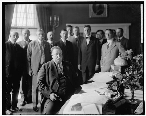 TAFT, WILLIAM HOWARD. AT DESK, WITH GROUP