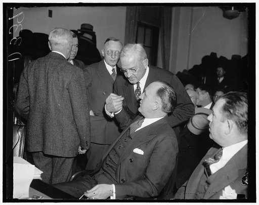 Last-minute huddle. Washington, D.C., Dec. 8. Harvey D. Gibson, (standing) President of the Manufacturers Trust Company, goes into a last minute huddle with John P. Murphy, Director of the Mid-America Corporation, before the Senate Inquiry into Railroad financing today. Gibson testified that his com