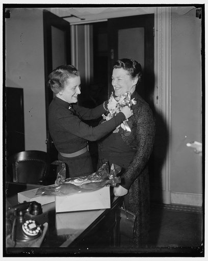 Adding the Feminine touch. Washington, D.C., Jan. 5. Rep. Mary T. Norton. Democrat of New Jersey, receives a corsage from her neice Mary Mc Dononaugh, as the final touch to her appearance before attending the opening session of the 75th Congress today