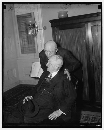 A House whisper. Washington, D.C., Jan. 7. Rep. Sam Rayburn, new majority leader of the House, whispers in to the ear of Senator Carter Glass, the monetary expert of the Senate, as both attend the conference today at the Capitol between administration leaders and Senate and House leaders to discuss 