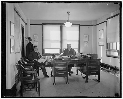 RFC Head at Work. Washington, D.C. Jesse Jones, Chairman of the Reconstruction Finance Corporation, at work in his office today. George Butler, of Houston, Texas, is shown with Chairman Jones