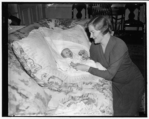 Secretary of War's youngest poses for first picture. Washington, D.C., March 24. Six-week-old Cooper Coolidge Woodring seems a bit camera-shy as he poses for his first picture today with his mother Mrs. Harry H. Woodring. This is the third child born to the Secretary of War and Mrs. Woodring since t