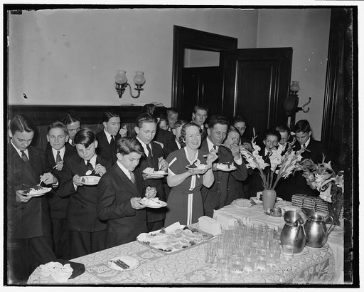 Louisiana Senator stands treat for Senate pages. Washington, D.C., April 22. Recalling how fond he was of ice cream when a youngster, Senator Allen J. Ellender, of Louisiana, played host to the Senate pages at an ice cream-and-cake party today at the Capitol. The Senator and Mrs. Ellender are shown 