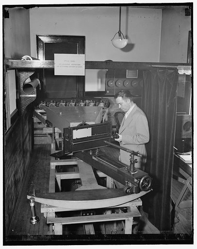 Testing airplanes lenses used in map making. Washington, D.C., May 6. Dr. F.E. Washer of the U.S. Bureau of Standards testing the lens for the airplane cameras that are used by the Army and Navy. There are lights in the rear of the columnmeters and exposures are made on the photographic plate in fro