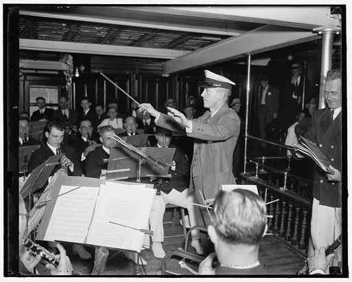 Rep. William P. Connery, Jr., of Massachusetts, tries his hand at leading the band while sailing down the Potomac with members of the National Press Club to attend the annual picnic at Quantico, Va., 5/22/1937